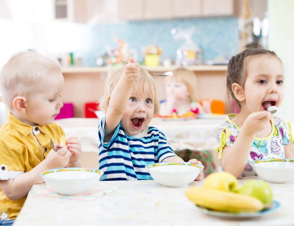 Excited children enjoying their meals together and happily eating