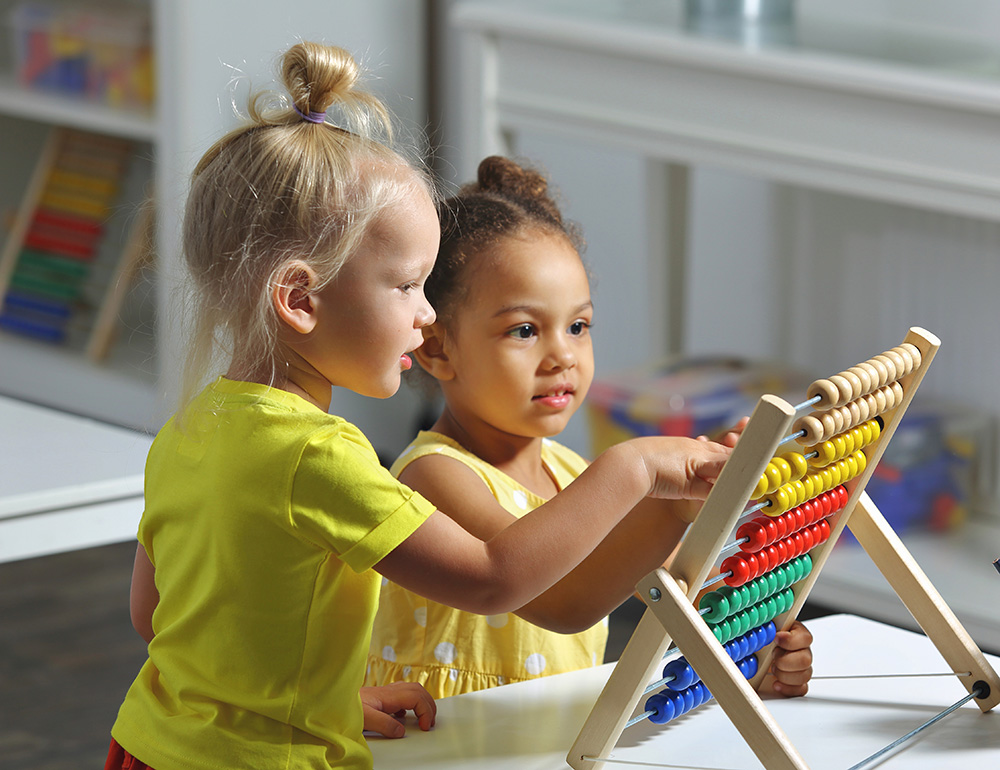 Two children playfully exploring an abacus, engaged in learning and enjoying each other's company