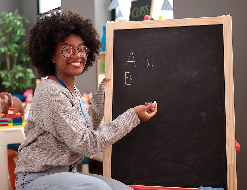 A cheerful teacher presenting letters on a chalkboard, promoting learning and engagement in a vibrant classroom environment.