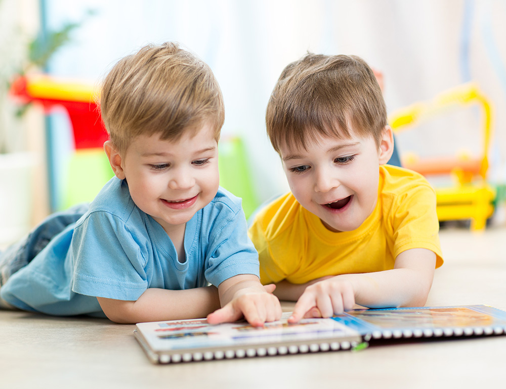 Two children eagerly reading a book together, sharing a moment of discovery and joy in a playful environment