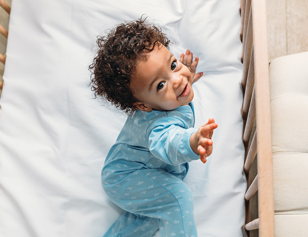 A playful toddler reaching out with a bright smile, showcasing their curiosity and joy while playing.