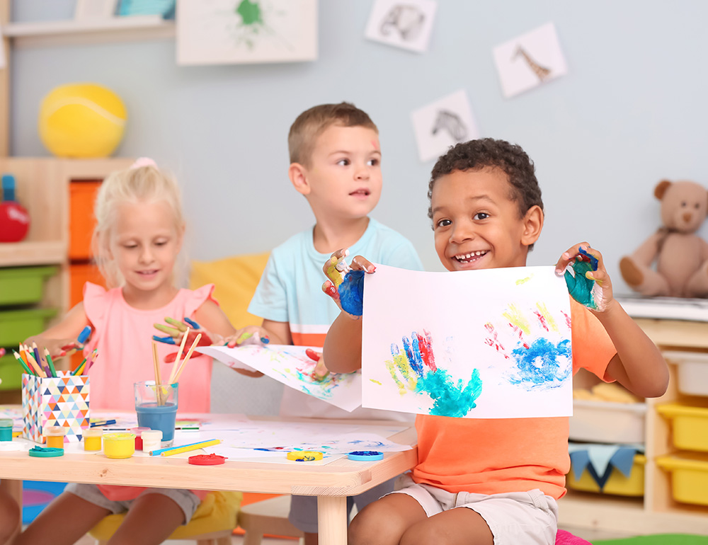 Children joyfully engaging in a creative art session, surrounded by colorful materials and cheerful decor in a bright room.