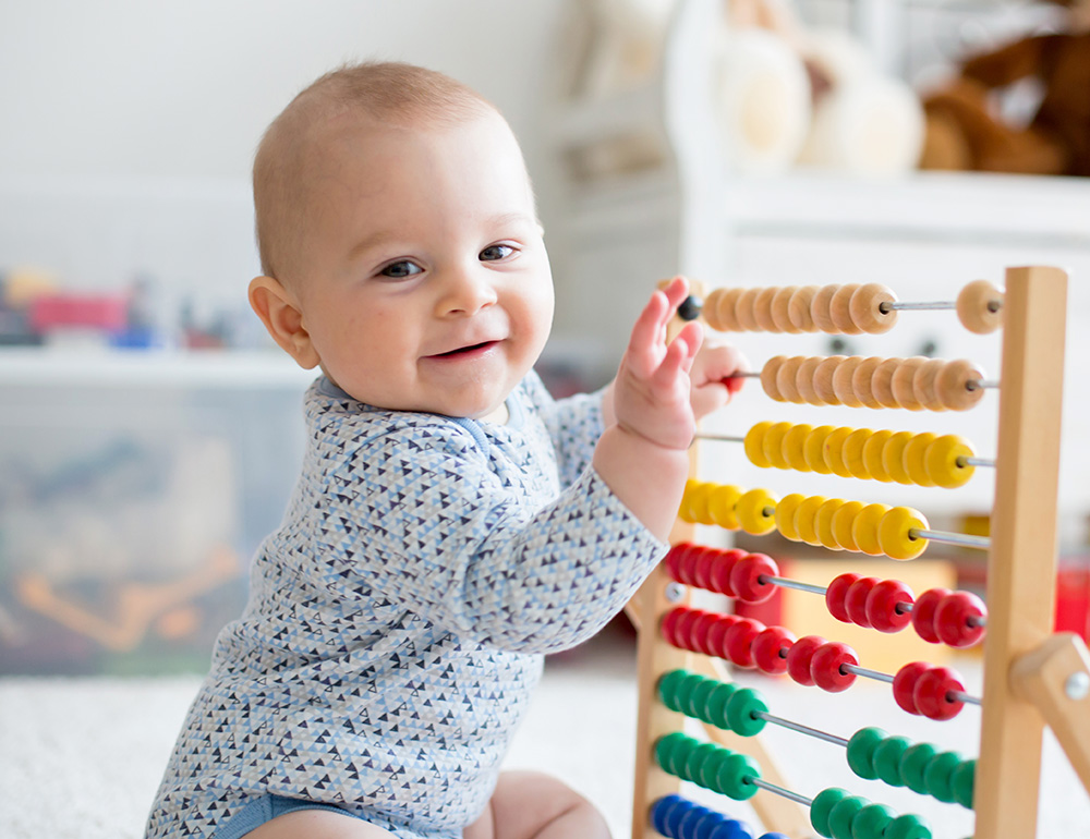 A smiling baby exploring a colorful abacus, engaging playful learning.