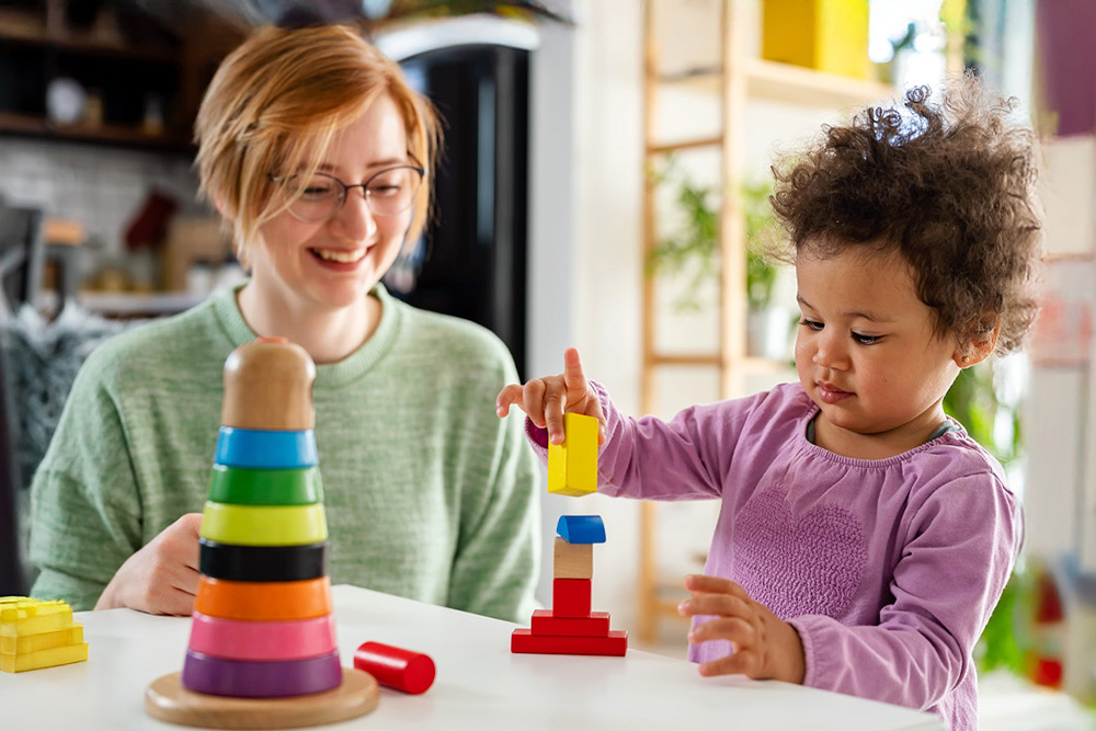 A teacher and child joyfully engage in play, showcasing the importance of guidance in learning through creativity